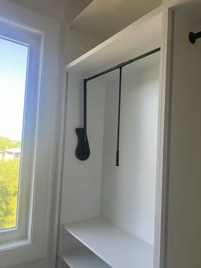 Pull-down wardrobe rod mounted high in a white closet section