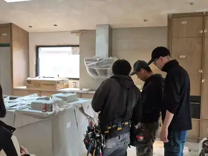Installation crew reviewing plans in a kitchen with wood-grain tall cabinets in place