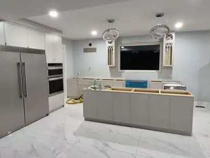 Kitchen island cabinets set in place before the countertop, beside a built-in fridge and ovens
