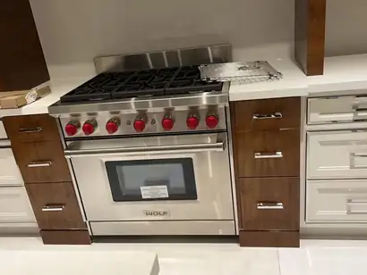 Gas range set between walnut drawer stacks and white shaker drawers