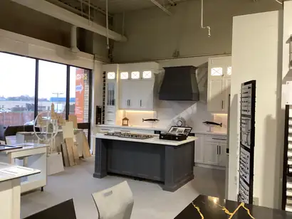 Showroom display kitchen with white cabinets, a range hood and a grey island